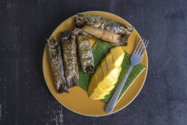 Tay tarzı tatlı, palmiye yapraklarımuz yapışkan pirinç ile sarı mango. Sarı mango ve yapışkan pirinç Tayland popüler geleneksel tatlı.