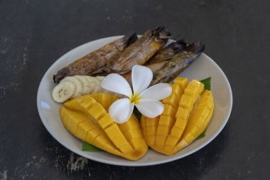 Tay tarzı tatlı, palmiye yapraklarımuz yapışkan pirinç ile sarı mango. Sarı mango ve yapışkan pirinç Tayland popüler geleneksel tatlı.