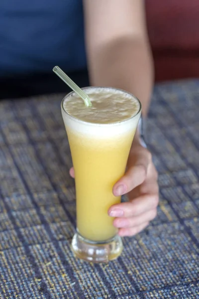 Mulher mão segurando um copo de suco de abacaxi fresco, close-up — Fotografia de Stock