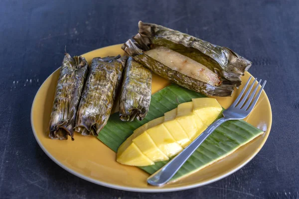 Tay tarzı tatlı, palmiye yapraklarımuz yapışkan pirinç ile sarı mango. Sarı mango ve yapışkan pirinç Tayland popüler geleneksel tatlı.