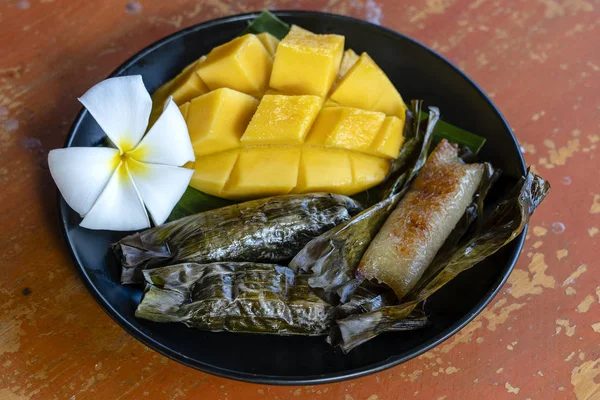 Tay tarzı tatlı, palmiye yapraklarımuz yapışkan pirinç ile sarı mango. Sarı mango ve yapışkan pirinç Tayland popüler geleneksel tatlı.