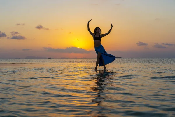 Młoda dziewczyna piękna tańczy na tropikalnej plaży na wodzie morskiej na rajskiej wyspie o zachodzie słońca. Koncepcja lato. Podróże wakacyjne. — Zdjęcie stockowe
