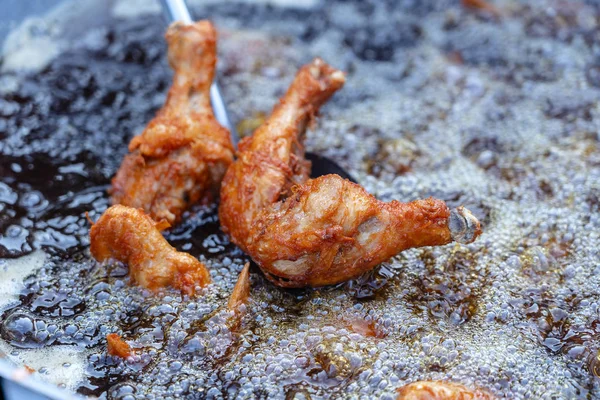 Tay sokak satıcısı Tayland sokak gıda pazarında ızgara tavuk bacağı et satıyor. Bir tavada kızartma tavuk bacakları yakın