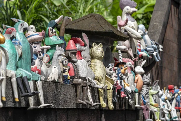 Viejos juguetes de recuerdos de madera en la valla de piedra cerca de la tienda de muñecas en Ubud, isla de Bali, Indonesia. Primer plano. — Foto de Stock