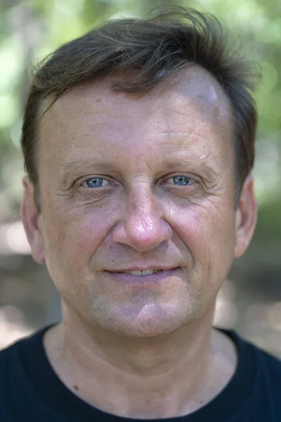 Portrait of a middle aged man resting on a background of green leaves in nature, closeup — Stock Photo, Image