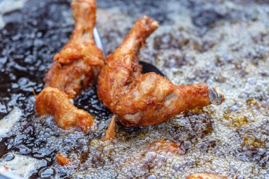 Tay sokak satıcısı Tayland sokak gıda pazarında ızgara tavuk bacağı et satıyor. Bir tavada kızartma tavuk bacakları yakın