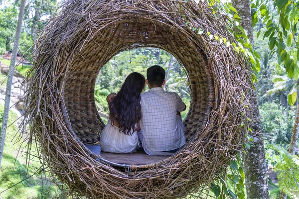 Mujer asiática y hombre disfrutando de su tiempo sentado en un nido de aves en la selva tropical cerca de las terrazas de arroz en la isla Bali, Indonesia — Foto de Stock