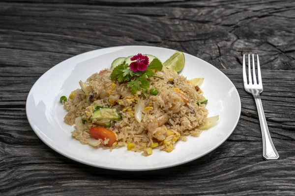 Stekt ris med räkor och grönsaker i en vit skål på ett gammalt träbord, närbild. Thailändsk mat, thailändskt kök — Stockfoto