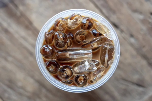 Ahşap arka planda buzlu kahve veya latte üst görünümü. Plastik cam buz ile siyah kahve, closeup