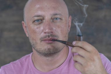 Pipo içen adam. Orta yaşlı bir adamın kapalı mekandaki portresi. Kötü alışkanlıklar, bağımlılık