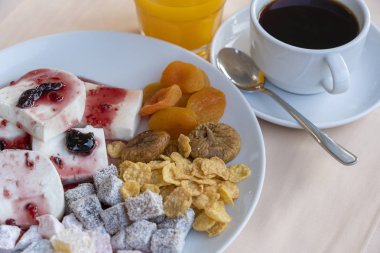 Lor peyniri üzerine meyveli yoğurt, kuru kayısı, incir, mısır gevreği ve fincan kahve dökülür. Kahvaltı konsepti.