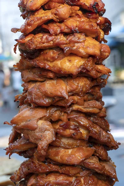 Large pieces of meat on a spit at street food market in Thailand. Crilled skewered chiken meat on spit. Fast food.