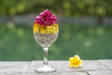 Chia tohum pudingle kırmızı dragon meyve, tutku meyve, mango ve avokado Yüzme Havuzu su, closeup arka günü kahvaltıda bir bardak içinde. Sağlıklı beslenme kavramı.