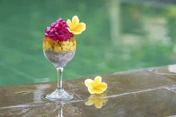 Chia semínka pudink s ovocem červený drak, mučenka, mango a avokádo ve sklenici na snídani na pozadí vody v bazénu, closeup. Koncept zdravého stravování. — Stock fotografie