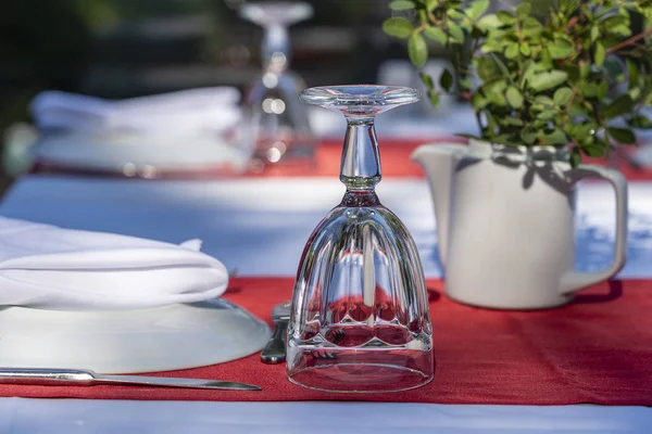 Elegantní stůl s vidličkou, nožem, skleněným vínem, bílým talířem a červeným ubrouskem v restauraci. Pěkný jídelní stůl s pořádanými stříbrnou a ubrousky na večeři — Stock fotografie