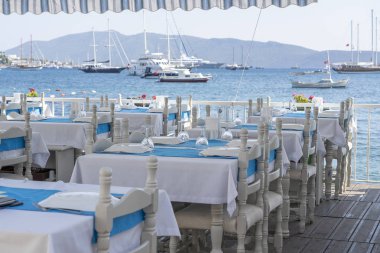 Restoranda çatal, bıçak, şarap bardağı, beyaz tabak ve mavi peçete ile zarif masa ayarı. Akşam yemeği için düzenlenmiş gümüş ve peçete ile Nice yemek masası seti