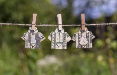 Yeşil doğa arka plan asılı dolar banknotyapılmış Origami gömlek. Dolar lar bir ipe asılı. Yakın çekim