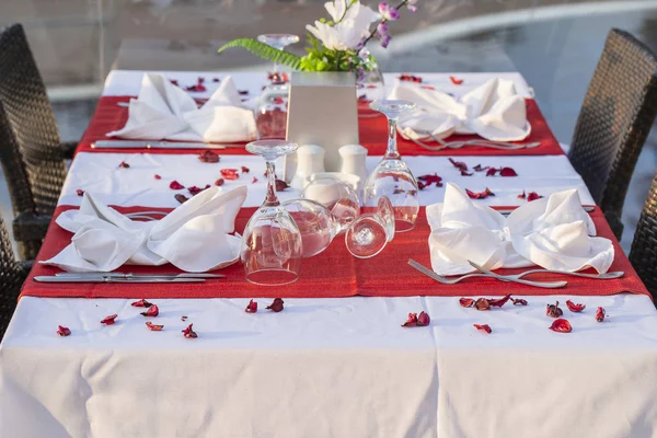 Elegante tafel setting met vork, mes, wijn glas, witte plaat en rode servet in restaurant. Mooie eettafel set met gearrangeerd bestek en servetten voor het diner — Stockfoto