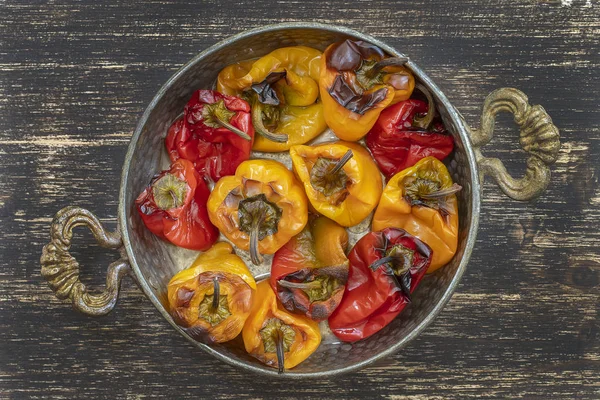 Pimentos vermelhos e amarelos assados. Pimentas em uma assadeira em uma mesa de madeira. Um prato vegetariano saudável e delicioso. Fechar, vista superior — Fotografia de Stock
