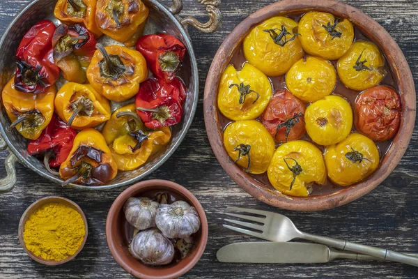 Pečené červené a žluté rajče a pepř. Rajčata a papriky v pečicí misce na dřevěném stole. Zdravá a lahodná vegetariánská jídla. Closeup, pohled shora — Stock fotografie