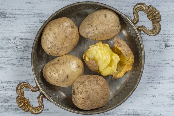 Baked potato in a metal bowl on a wooden table, simple vegetarian food. Boiled potatoes on wooden table, close up — Stock Photo, Image