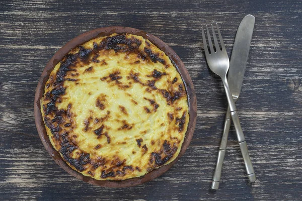 Sweet Cottage Cheese braadpan met rozijnen en griesmeel op houten tafel. Keramische kom met gebakken kwark braadpan, close-up, bovenaanzicht — Stockfoto