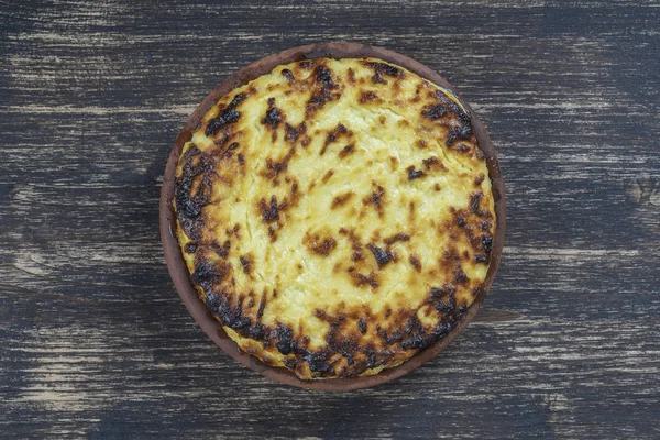 Sweet Cottage Cheese braadpan met rozijnen en griesmeel op houten tafel. Keramische kom met gebakken kwark braadpan, close-up, bovenaanzicht — Stockfoto