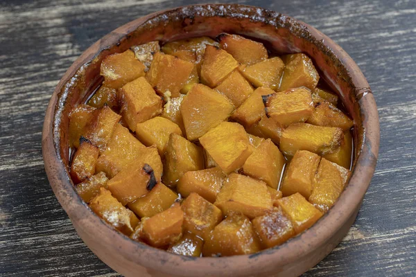 Ψητή κίτρινη κολοκύθα με μέλι, ελαιόλαδο και μπαχαρικά σε ένα πιάτο στο ξύλινο τραπέζι. Φαγητό για χορτοφάγους. Closeup — Φωτογραφία Αρχείου