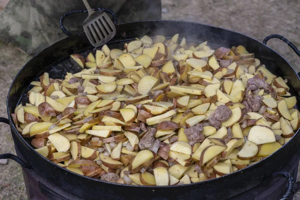 Patatas asadas en una sartén grande. Las papas jóvenes se fríen en aceite, comida callejera —  Fotos de Stock