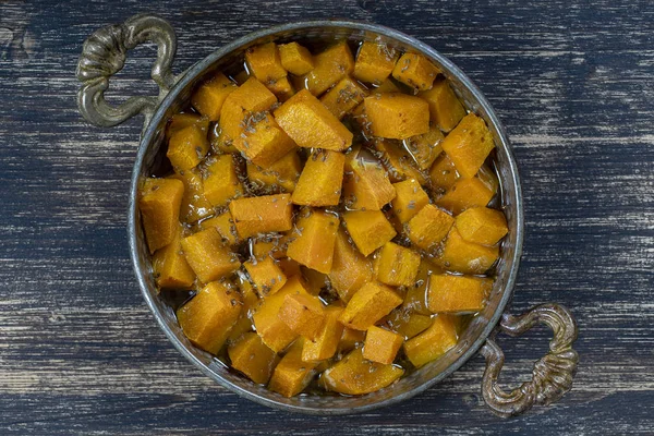 Ψητή κίτρινη κολοκύθα με μέλι, γλυκάνισο, ελαιόλαδο και μπαχαρικά σε ένα πιάτο στο ξύλινο τραπέζι. Φαγητό για χορτοφάγους. Closeup — Φωτογραφία Αρχείου