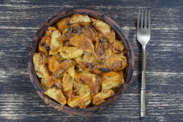 Patata al forno e carota con formaggio sul tavolo di legno, da vicino. Ciotola di ceramica con patate e fette di carota sfondo — Foto Stock