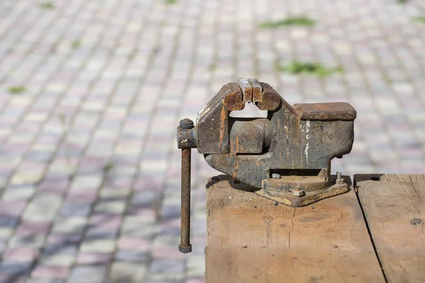 Starý rezavý svěrák pro kovové výrobky na dřevěném stole, venku, zblízka — Stock fotografie