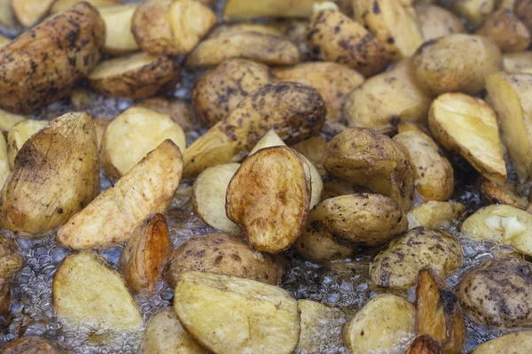 Patatas asadas en una sartén grande. Las papas jóvenes se fríen en aceite, comida callejera — Foto de Stock