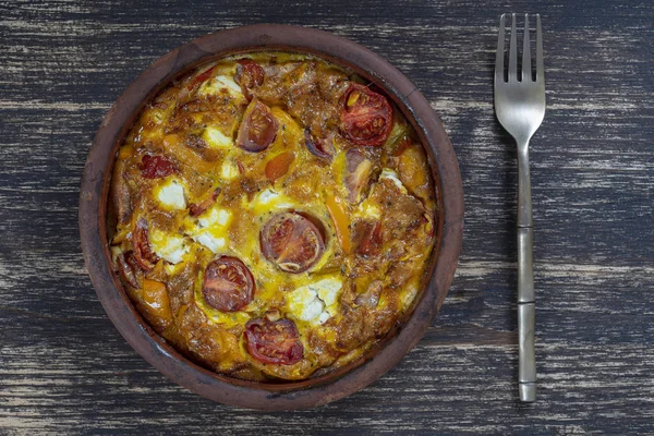 Ciotola in ceramica con frittata di verdure, semplice cibo vegetariano. Frittata con pomodoro, pepe, cipolla e formaggio feta sul tavolo di legno, da vicino. frittata di uova italiane — Foto Stock