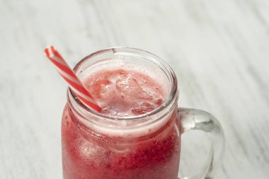 Beyaz masaüzerinde cam kupa taze organik kırmızı smoothie, yakın. Ferahlatıcı yaz meyve içeceği. Sağlıklı beslenme kavramı. Kızılcık ve ahududu smoothie