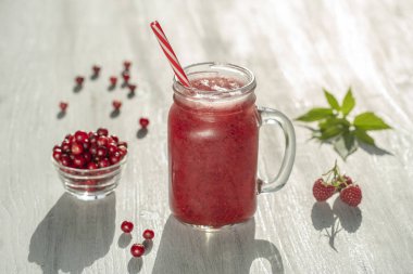 Beyaz masaüzerinde cam kupa taze organik kırmızı smoothie, yakın. Ferahlatıcı yaz meyve içeceği. Sağlıklı beslenme kavramı. Kızılcık ve ahududu smoothie