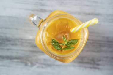 Beyaz ahşap masa üzerinde cam kupa taze organik sarı smoothie, yakın. Ferahlatıcı yaz meyve içeceği. Sağlıklı beslenme kavramı. Deniz dikeni smoothie