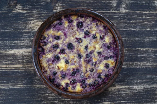 Sweet cottage cheese casserole with black currant and semolina on wooden table. Ceramic bowl with baked cottage cheese casserole — Stock Photo, Image