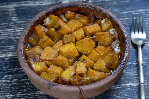 Gebackener gelber Kürbis mit Honig, Olivenöl und Gewürzen auf einem Teller auf dem Holztisch. Vegetarische Kost. Nahaufnahme — Stockfoto