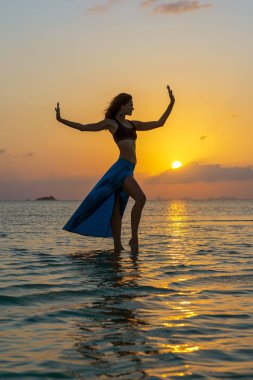 Genç güzel kız tropikal sahilde dans ediyor deniz suyunda, para