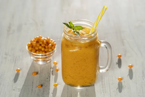 Smoothie amarelo orgânico fresco na caneca de vidro na mesa de madeira branca, de perto. Bebida refrescante de frutas de verão. O conceito de alimentação saudável. Smoothie espinheiro-do-mar — Fotografia de Stock