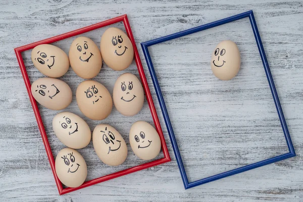 Imagem moldura vermelha e azul e muitos ovos engraçados sorrindo no fundo da parede de madeira, close-up. Ovos família emoção rosto retrato. Conceito comida engraçada — Fotografia de Stock