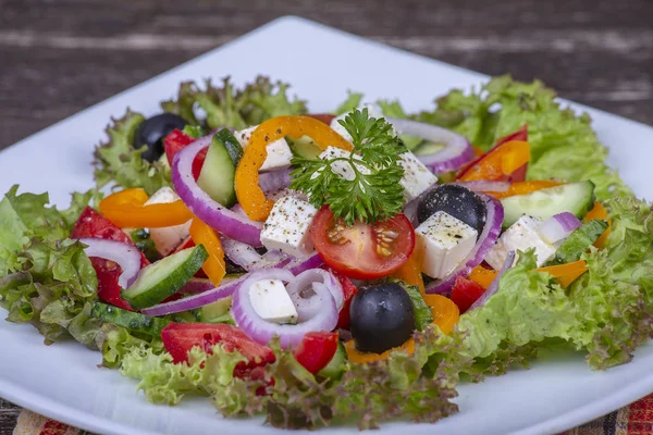 Greek salad of fresh cucumber, tomato, sweet pepper, lettuce, red onion, feta cheese and olives with olive oil. Healthy food — Stock Photo, Image