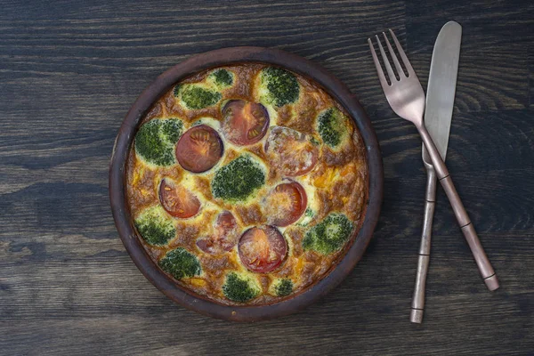 Keramisk skål med grönsakfrittata, enkel vegetarisk mat. Frittata med ägg, tomat, peppar, lök, broccoli och ost på träbord. Italiensk äggomelett — Stockfoto