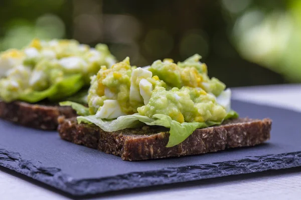 Sandwich con aguacate y huevo escalfado - concepto de desayuno saludable, primer plano —  Fotos de Stock