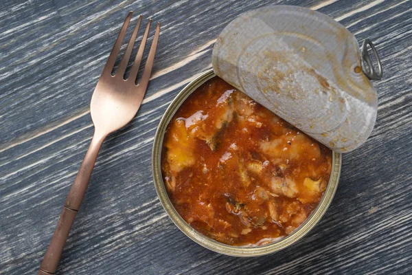 Open sprot in blik in tomatensaus op een houten ondergrond, close-up, bovenaanzicht — Stockfoto