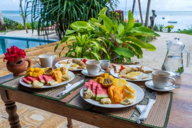 Otel restoranı, Zanzibar adası, Tanzanya, Afrika 'da deniz kenarındaki plajda iki kişilik meyve, kahve ve muzlu krep. Üst görünüm, tablo ayarı.