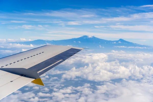 東アフリカのタンザニアの白い雲の中のキリマンジャロ火山の飛行機の窓からの眺め — ストック写真