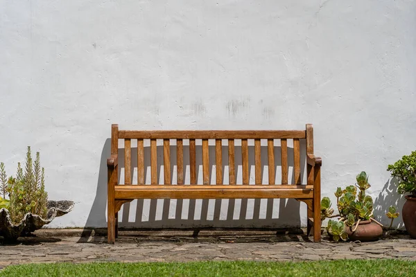 Houten Bank Voorzijde Van Een Witte Stenen Muur — Stockfoto