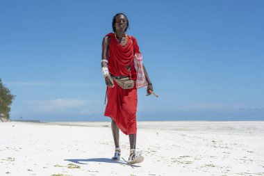 Zanzibar, Tanzanya - 28 Ekim 2019: Geleneksel giysiler içinde Afrikalı adam masai okyanus kenarında, Tanzanya, Doğu Afrika 'daki Zanzibar adasının kumsalında duruyor.